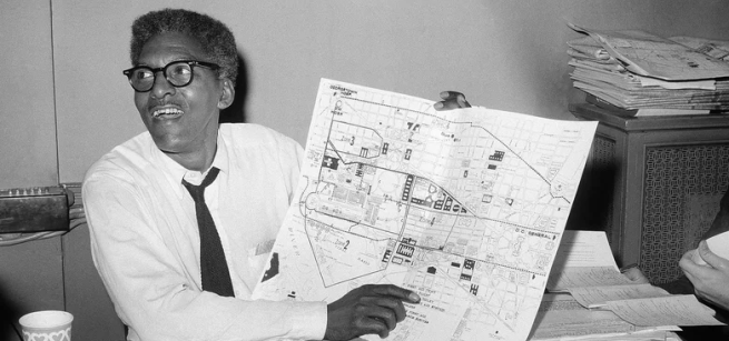 Bayard Rustin holding up a city map and pointing at it.