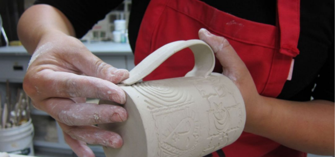 A person is making a ceramic mug. 