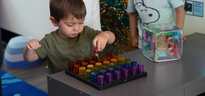 A young boy playing with sensory toys