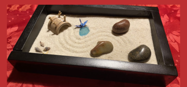 Black lacquered box with sand and rocks with rake marks with a red background 