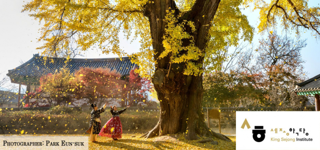 A woman under a tree with a building in the background.