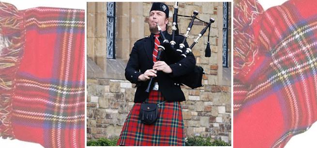 A man wearing scottish regalia is holding a bagpipe and blowing into a tube