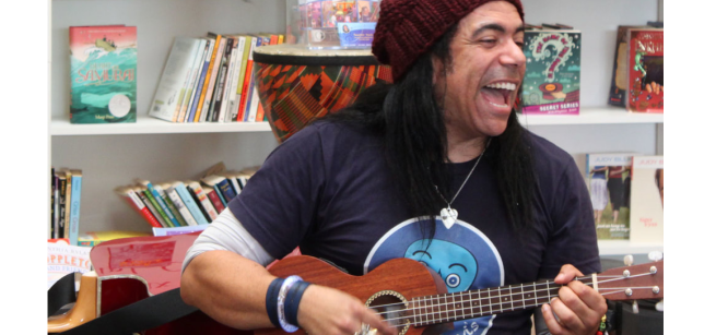 Teacher Davis strumming a ukelele and singing