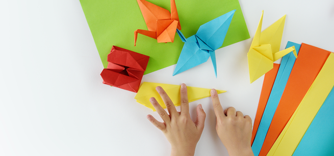 Child's hands folding paper into different shapes