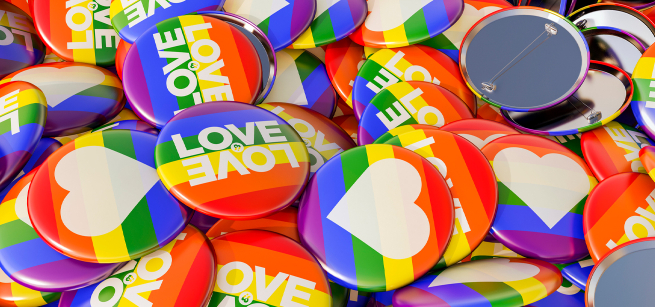 Many brightly colored pins featuring rainbow backgrounds, hearts, and the words "love is love"