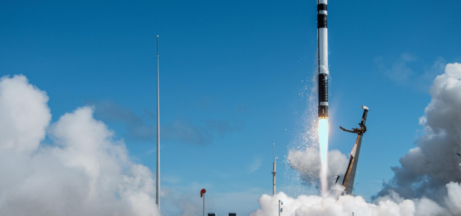 rocket blasting off with smoke and a blue sky