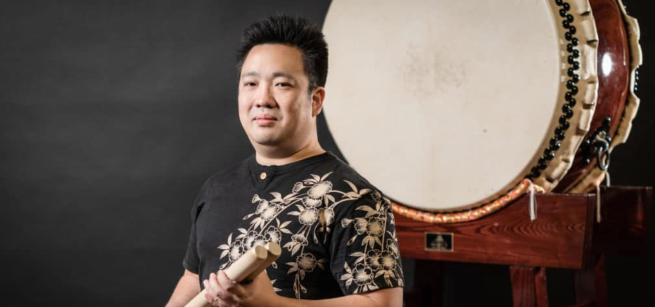 A man stands in front of a Japanese taiko drum