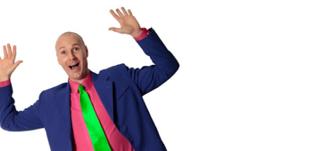 Man wearing a brightly colored suit and tie raising his hands in the air and smiling.