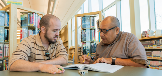 An instructor and a student review a workbook.