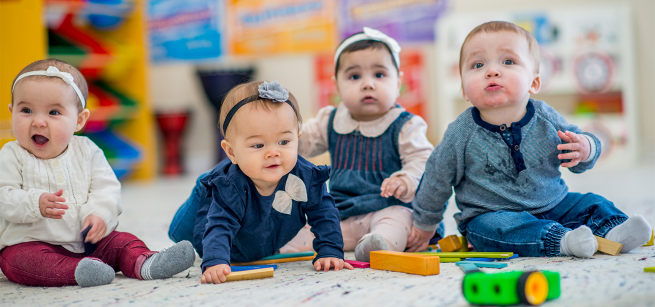 Babies crawl on the floor towards toys