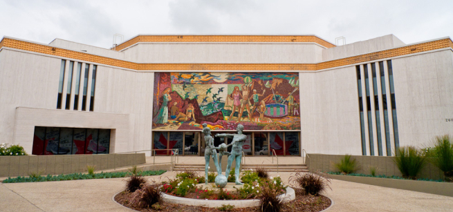 Photo of a bank building with a mural and a statue.