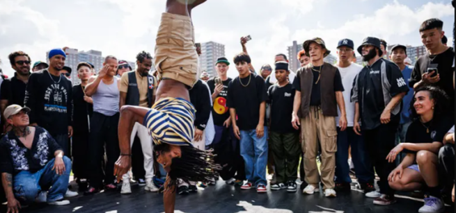 Onlookers watching a breakdancing teen