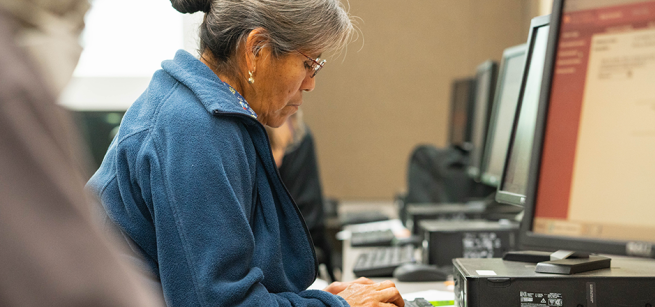 Row of desk top computers and a adult woman looking at them