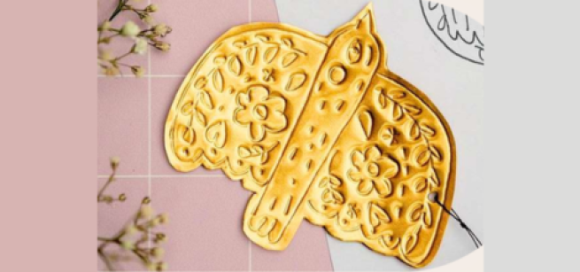 image shows a gold tin hojalata tin ornament with dried flowers in the background
