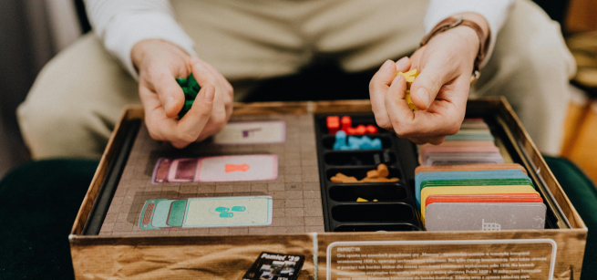 Person holding game pieces over a game board as if about to roll a turn.