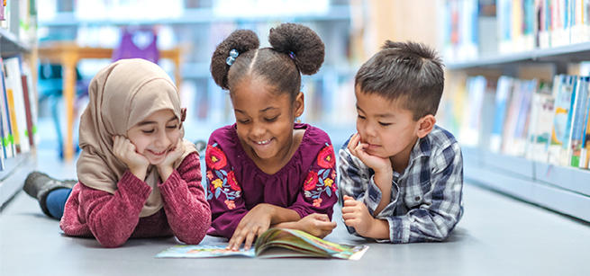 three kids reading a book together