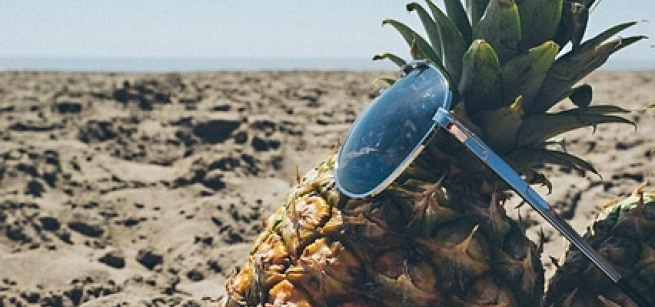 A pineapple at the beach, wearing sunglasses.