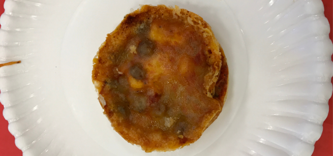 A mini pizza on a paper plate