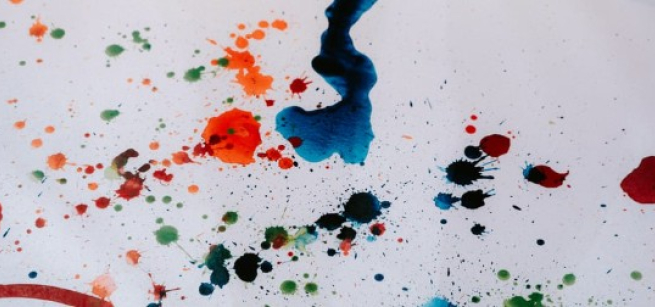 Different colors of paint splashed onto white paper