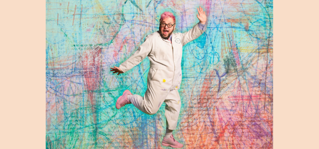 Ricky Rainbow Board jumping in front of a colorful background. 