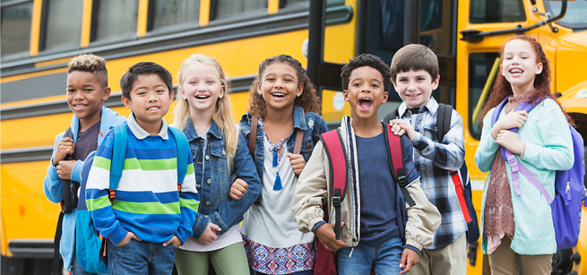 kids with backpacks in front of a school bus