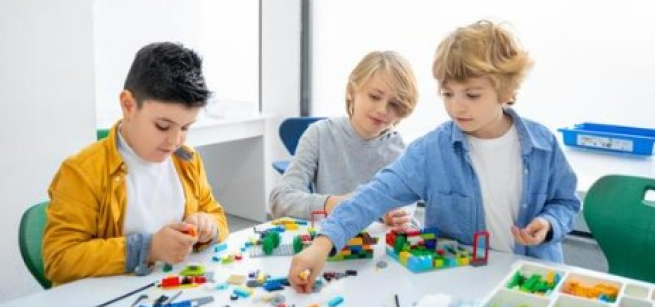 Three boys playing with building bricks together. 