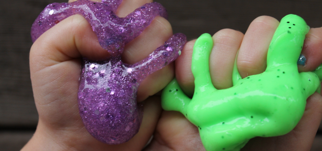 hands squishing purple glittery and green slime