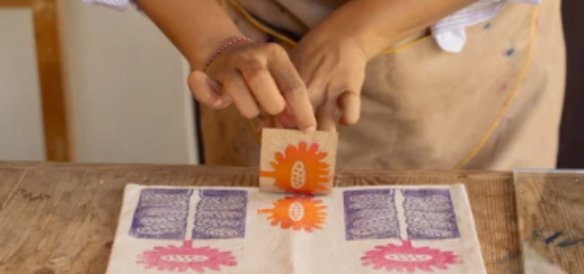 A person stamping a canvas bag at a table