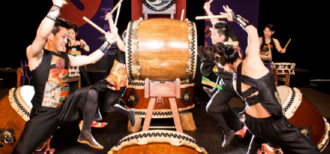 Adults drumming on drums.