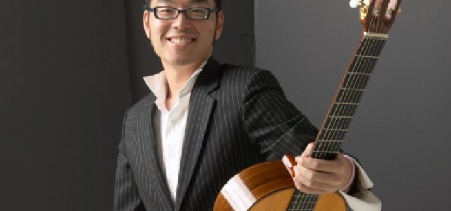 A man holding a guitar and looking at the camera 