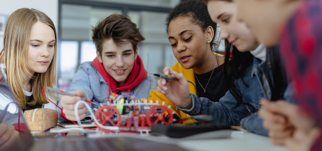 Teens looking at a robot