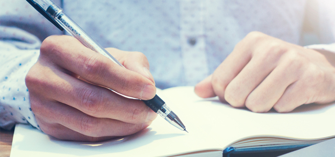 hands writing in notebook