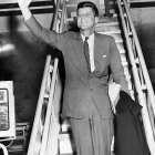 President John F. Kennedy waving while boarding a plane.
