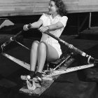 Ann Morris, Metro-Goldwyn-Mayer actress, demonstrates how she exercises on the rowing machine in the studio gym. Circa 1939 – Works Progress Administration Collection