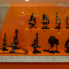 A glass display of various microscopes throughout the years.