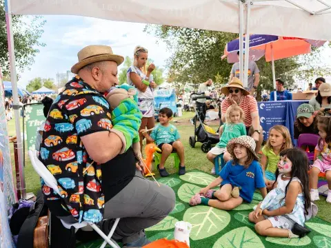 librarian leads children in outdoor storytime with puppets