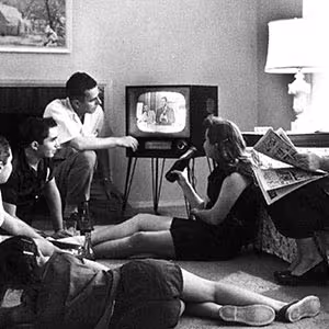 People laying in front of a television in the 1960s.