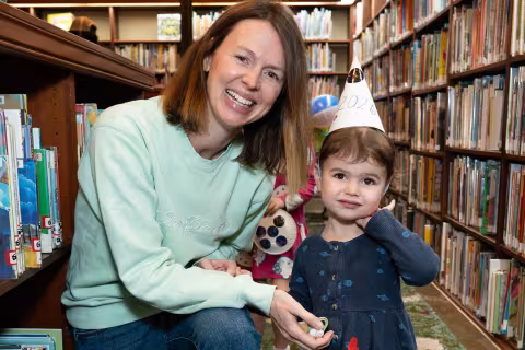 family stands between bookshelves