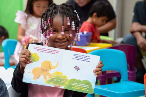 young child holds up book