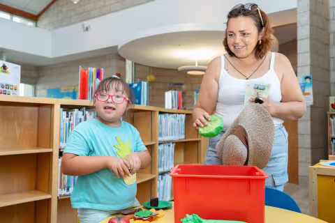 young child and parent play with toys at library