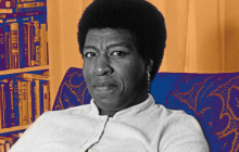 Author Octavia E. Butler sitting on a chair in front of a bookshelf