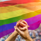 lgbtqia flag and hands intertwined