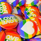 Many brightly colored pins featuring rainbow backgrounds, hearts, and the words "love is love"