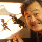 Sunny Seki holds shadow puppets against a projected screen.
