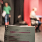 Person holding a script behind a stage curtain