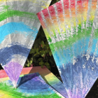 A pile of rainbow-painted kites against a leafy background.