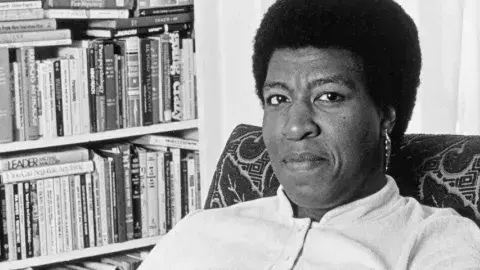Octavia E. Butler seated by her bookcase, 1986