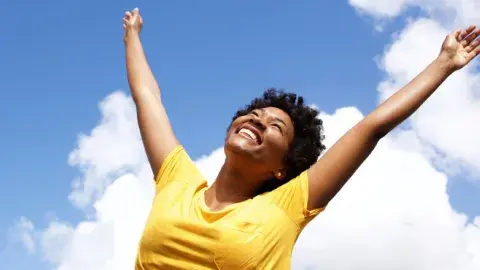 cheerful young woman with hands raised