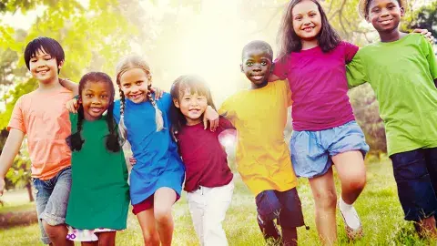 Smiling, diverse kids walking side by side in a grassy playground