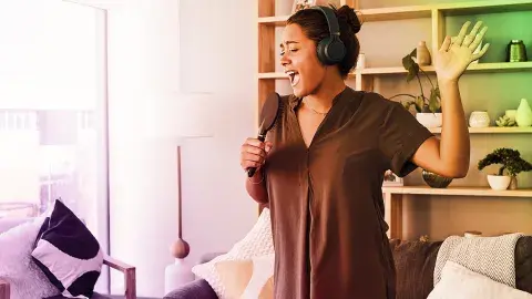 Young person with her headphones and singing into her hair bursh.